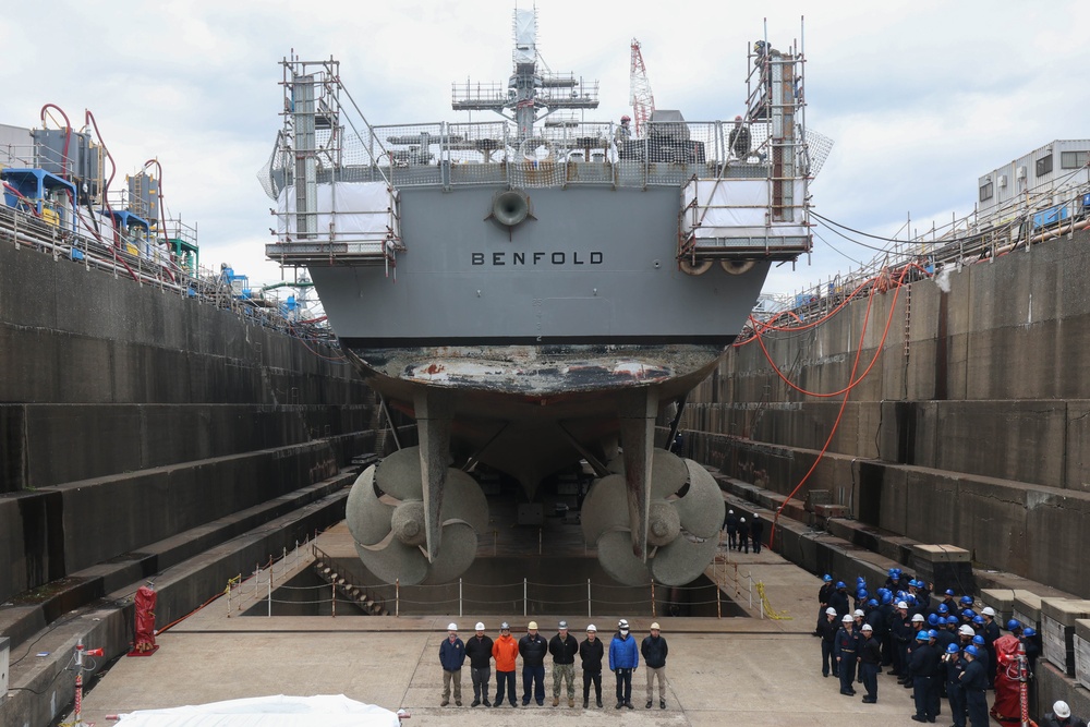 Contractors and Sailors pose for a group photo in front of USS Benfold (DDG 65) in a dry dock onboard Commander, Fleet Activities Yokosuka