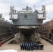 Sailors pose for a group photo in front of the USS Benfold (DDG 65) in a dry dock onboard Commander, Fleet Activities Yokosuka