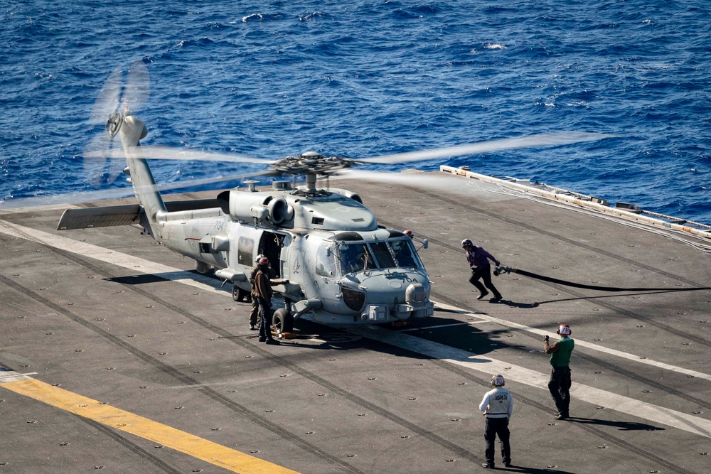 Sailors refuel an MH-60R Sea Hawk