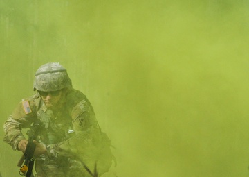 Civil Affairs Soldier assaults urban objective through yellow smoke cover
