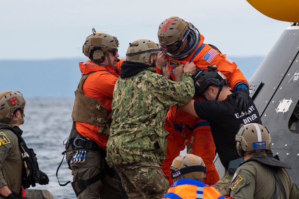 Navy Divers assist astronaut out of crew module test article during Underway Recovery Test 11