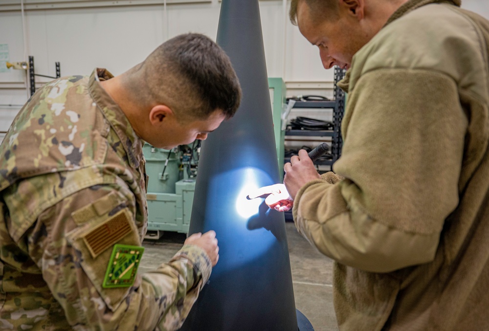 MUNS technicians work on Mark 21 Reentry Vehicle Trainer looking for defects
