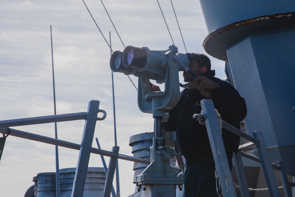 USS John S. McCain Sailor looks through the ship's binoculars