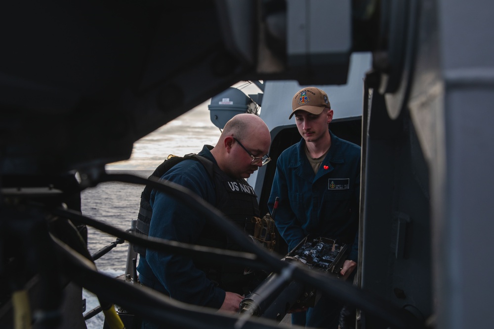 Sailors conduct maintenance on the 25mm gun