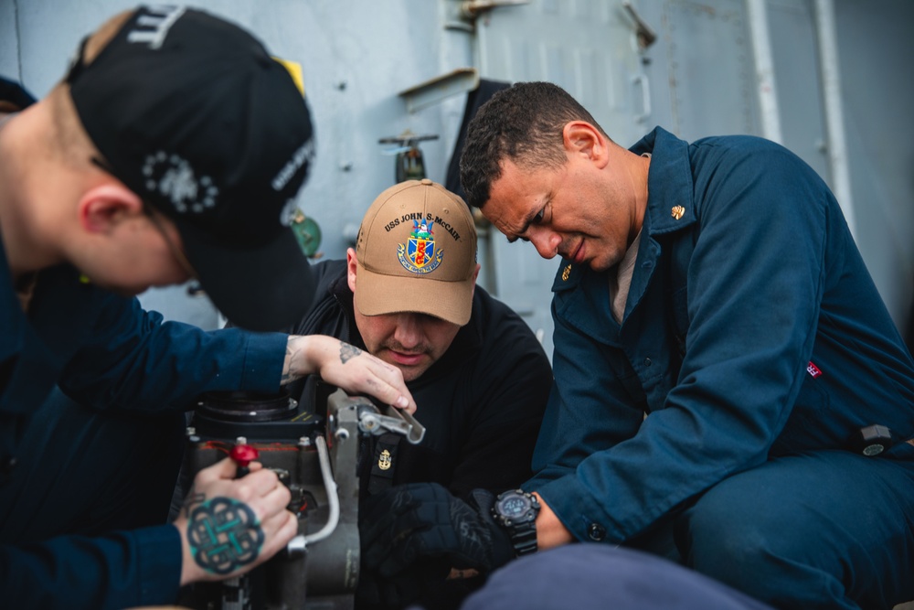 Sailors conduct maintenance on the 25mm gun