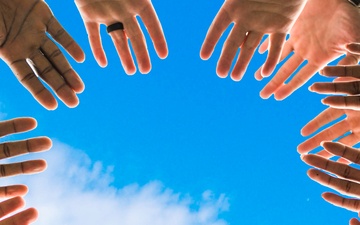 Generic hands raised against blue sky background graphic