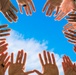 Generic hands raised against blue sky background graphic