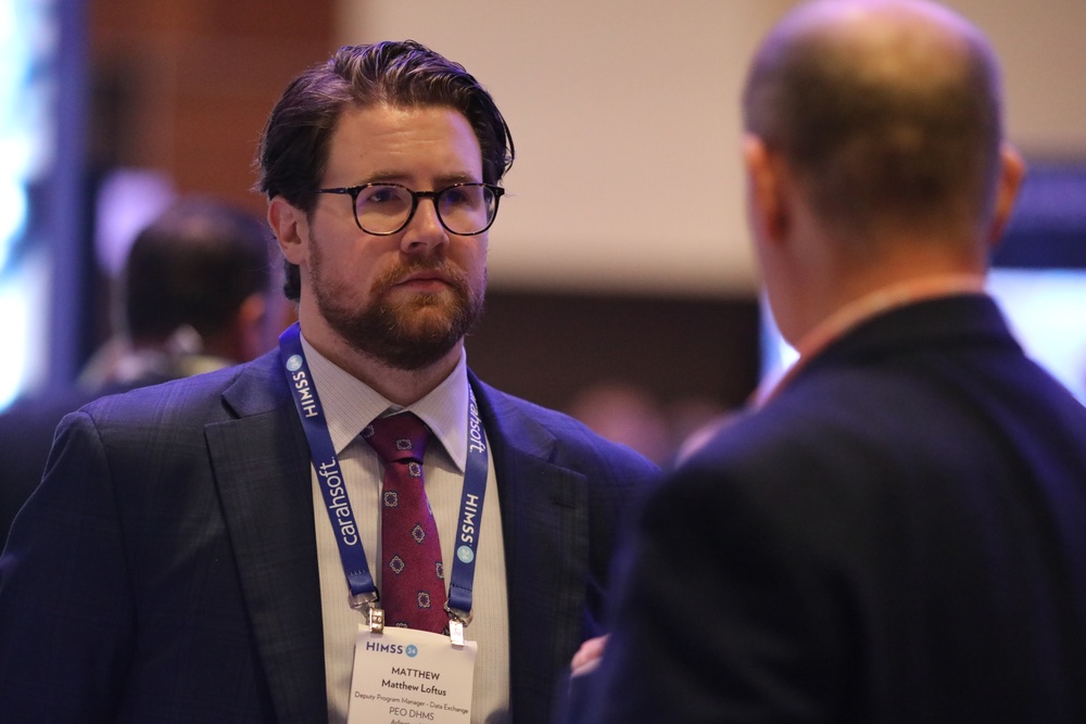 Matthew Loftus meets with visitors to the FEHRM kiosk at the HIMSS Conference