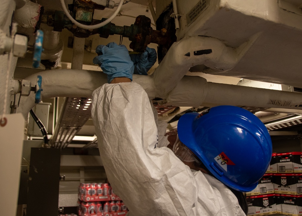 USS Ronald Reagan (CVN 76) Sailor repairs lagging in a storeroom