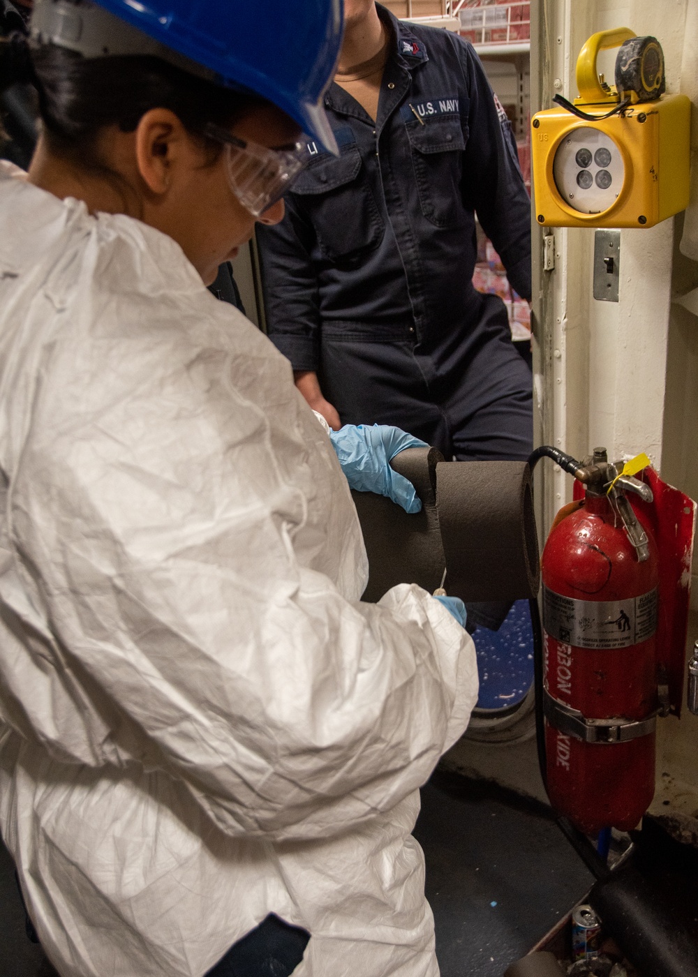 USS Ronald Reagan (CVN 76) Sailor repairs lagging in a storeroom