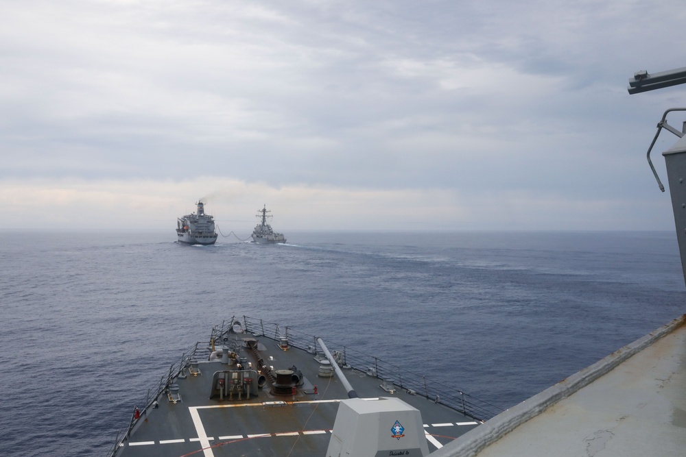 The USS Ralph Johnson conducts a replenishment-at-sea with USNS Yukon in the Philippine Sea