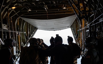 Special forces service members jump out of the back of a C-130 Hercules aircraft