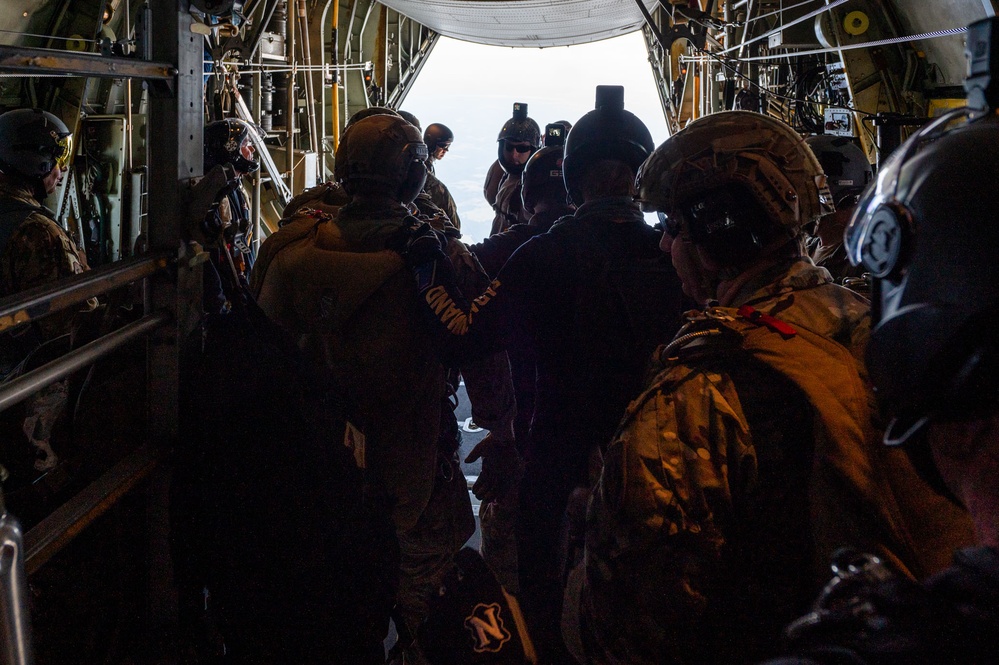 Special forces service members jump out of the back of a C-130 Hercules aircraft