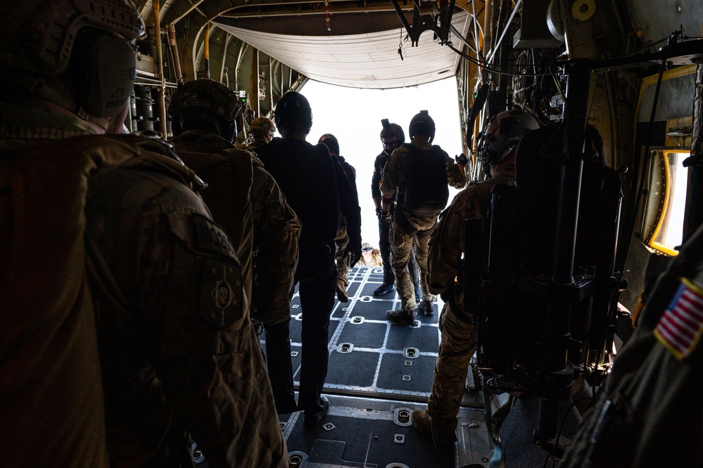 Special forces service members jump out of the back of a C-130 Hercules aircraft