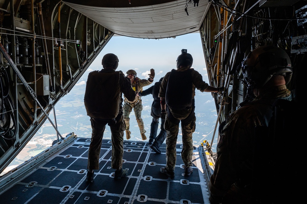 Special forces service members jump out of the back of a C-130 Hercules aircraft