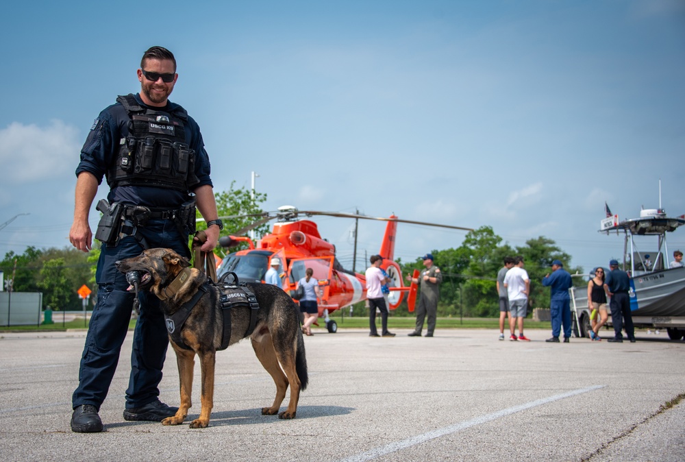 Petty Officer 1st Class Daniel Alati, a maritime enforcement specialist assigned to Maritime Safety & Security Team Houston, poses for a photo with his K9 partner, Chief Petty Officer Simba, during Coast Guard Sector Houston-Galveston’s Community Day in Houston, Texas, April 20, 2024. Simba is trained in explosives detection and deploys throughout the U.S., safeguarding major events and protecting ports and waterways. (U.S. Coast Guard photo by Chief Petty Officer Corinne Zilnicki)