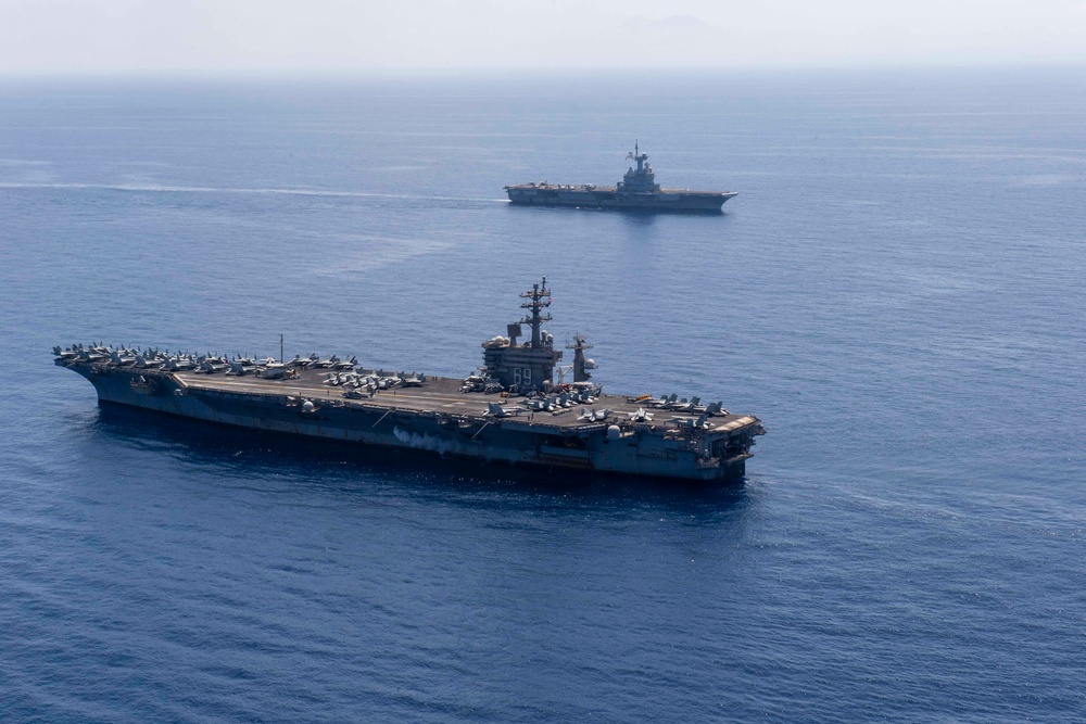 FS Charles De Gaulle (R91) passes alongside the Nimitz-class aircraft carrier USS Dwight D. Eisenhower (CVN 69) in the Mediterranean Sea