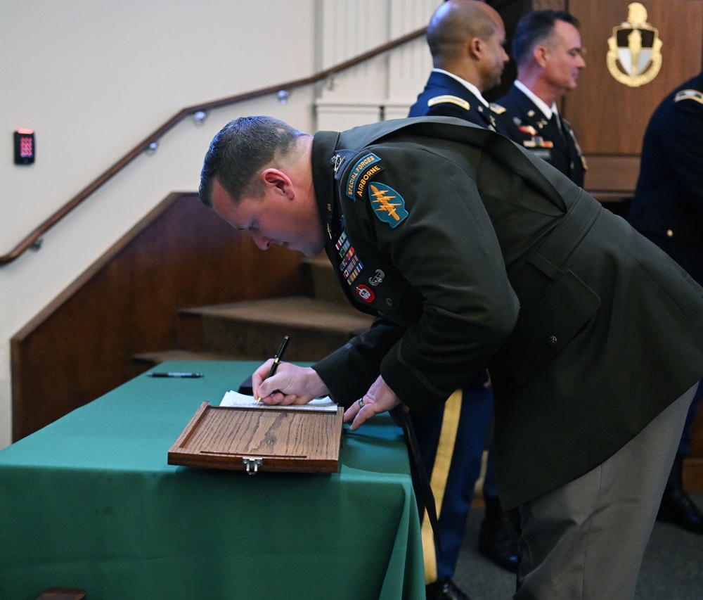 A Soldier from the U.S. Army John F. Kennedy Special Warfare Center and School signs a regimental logbook during a  Graduation Ceremony