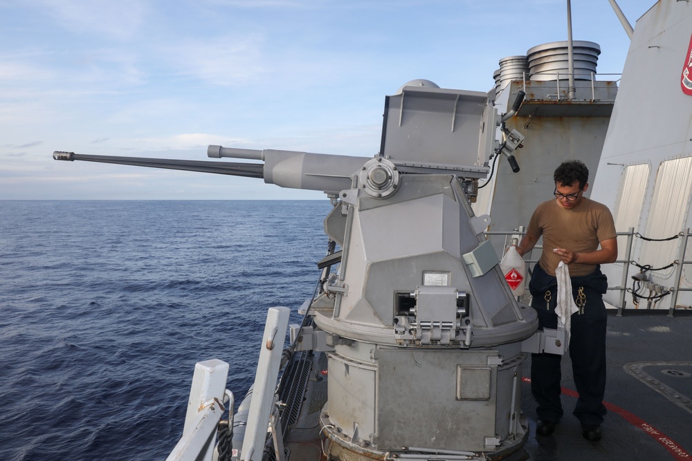 Sailors aboard the USS Howard perform maintenance on an MK 38 25mm chain gun in the South China Sea