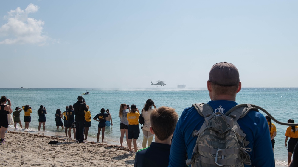 U.S. Maritime service members and civilians observe a helo-drop during the “Top Gun” Beach Olympics event in Miami Beach, Fla., during Fleet Week Miami, May 11, 2024.