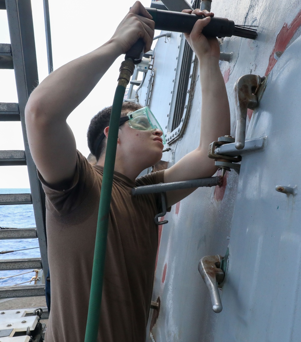 Sailors aboard the USS Howard perform maintenance on the ship's exterior bulkhead in the South China Sea