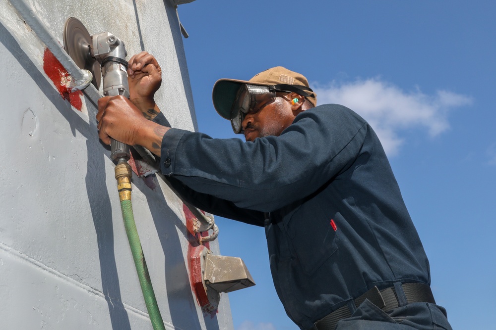 Sailors aboard the USS Howard conduct maintenance on the ship's exterior bulkhead in the South China Sea