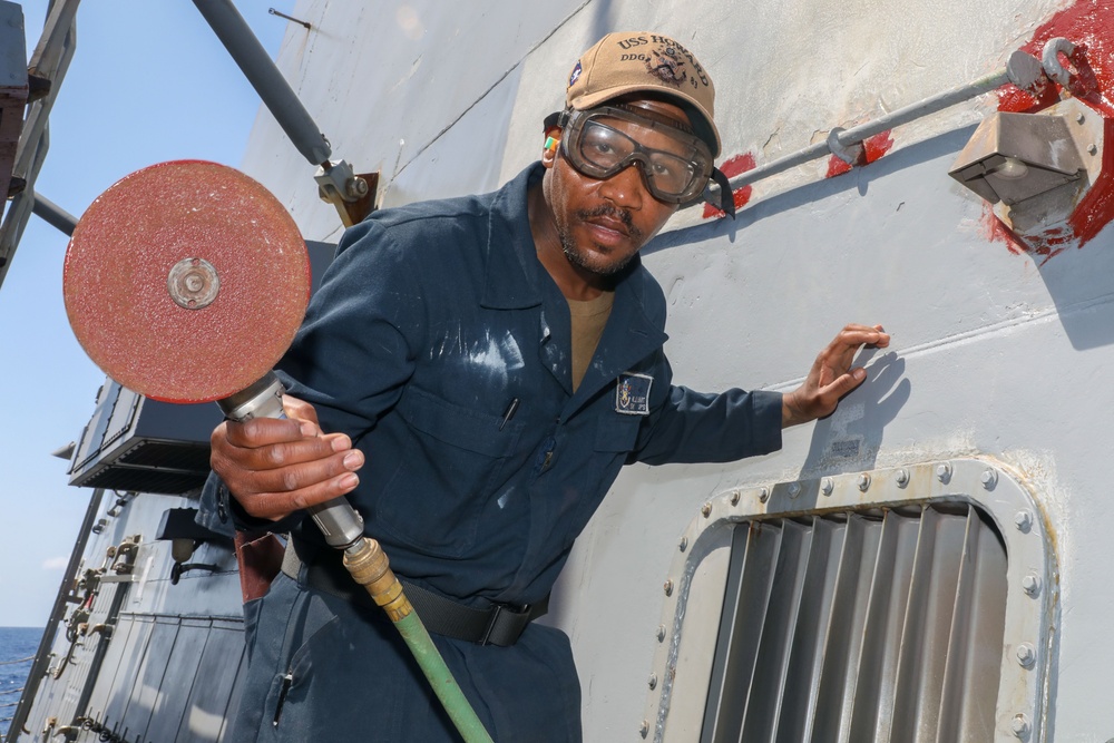 Sailors aboard the USS Howard conduct maintenance on the ship's exterior bulkhead in the South China Sea