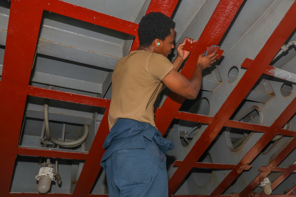 Sailors aboard the USS Howard conduct maintenance on the ship's exterior bulkhead in the South China Sea