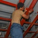 Sailors aboard the USS Howard conduct maintenance on the ship's exterior bulkhead in the South China Sea