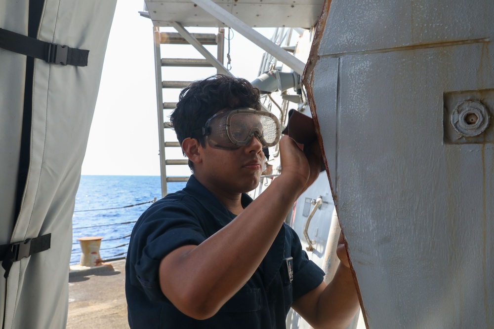 Sailors aboard the USS Howard conduct maintenance on the ship's exterior bulkhead in the South China Sea