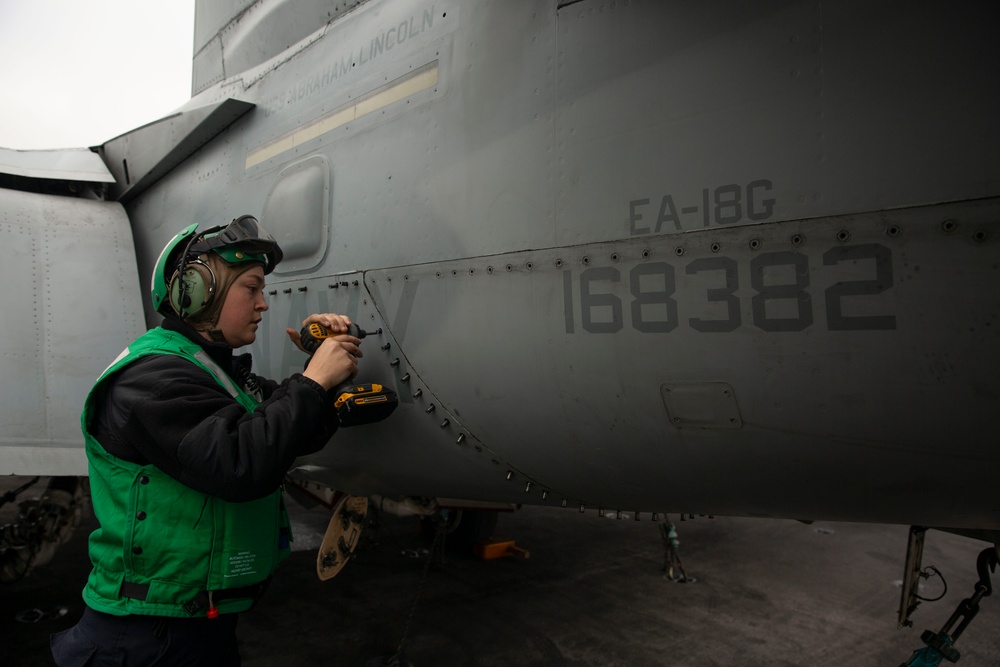 Sailor conducts aircraft maintenance on an aircraft aboard Abraham Lincoln