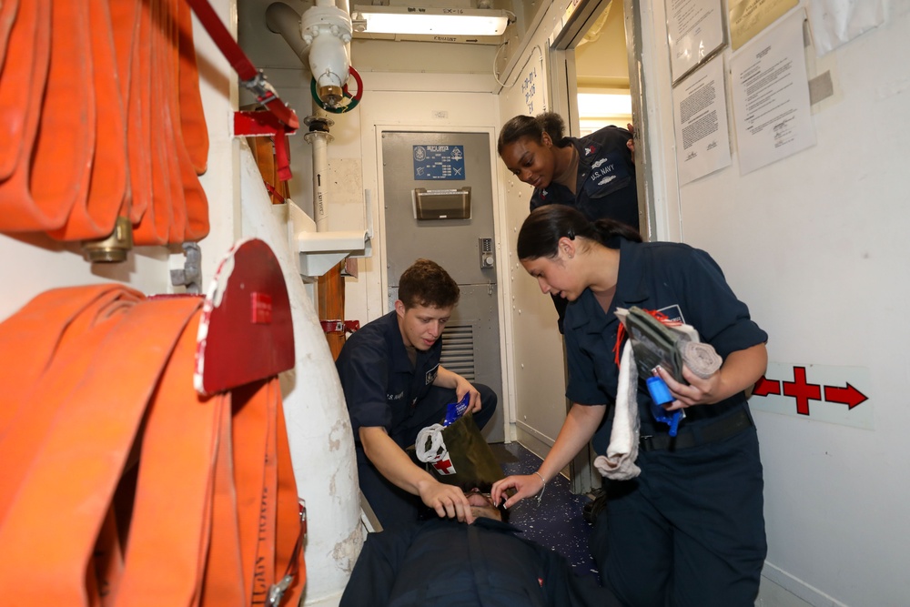 Sailors aboard the USS Howard conduct a medical emergency drill in front of the ship's store in the South China Sea