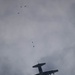 Service members and civilians perform a freefall jump near Amfreville, France