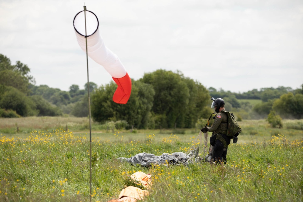 Service members and civilians perform a freefall jump near Amfreville, France