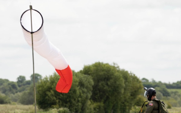 Service members and civilians perform a freefall jump near Amfreville, France