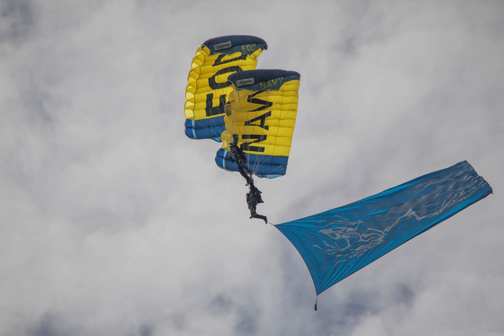 Service members and civilians perform a freefall jump near Amfreville, France