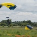 Service members and civilians perform a freefall jump near Amfreville, France