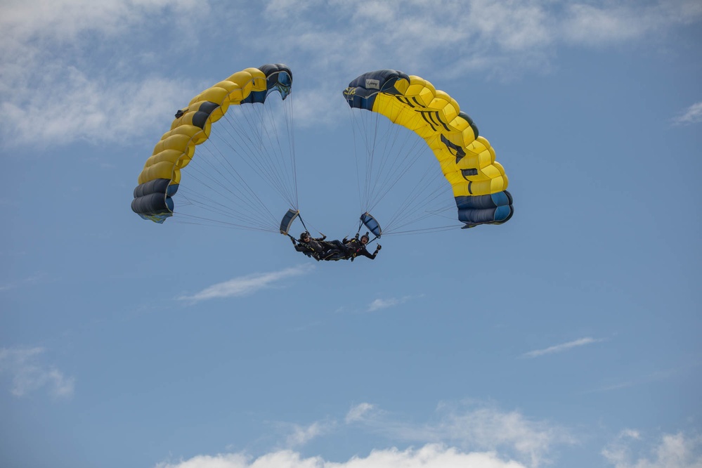 Service members and civilians perform a free-fall jump near Amfreville, France