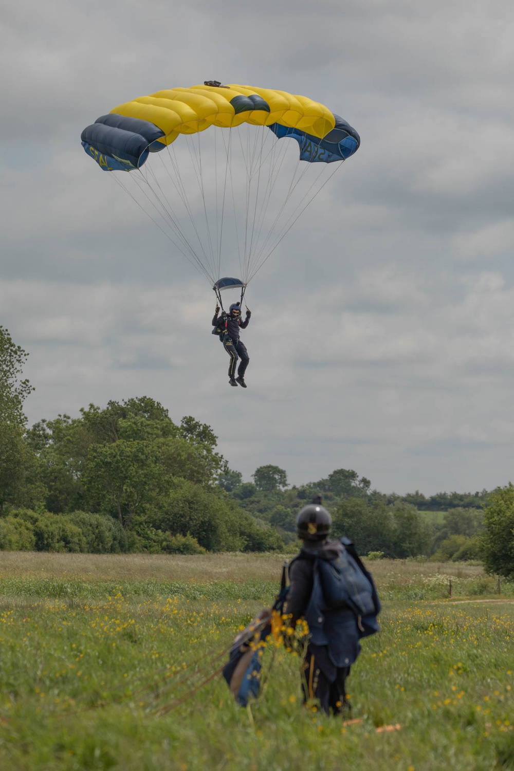 Service members and civilians perform a freefall jump near Amfreville, France