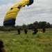 Service members and civilians perform a free-fall jump near Amfreville, France