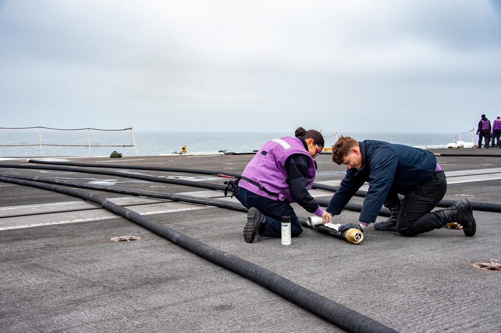 USS Carl Vinson (CVN 70) Sailors Stencil Hoses On The Flight Deck