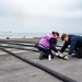 USS Carl Vinson (CVN 70) Sailors Stencil Hoses On The Flight Deck