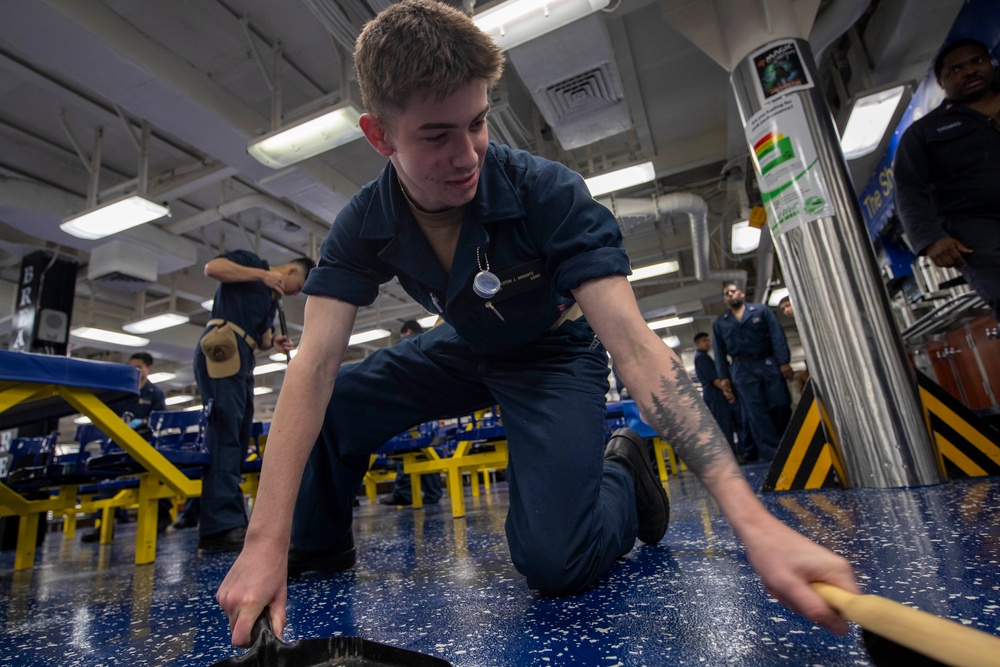 Midshipmen clean the mess decks aboard USS Tripoli