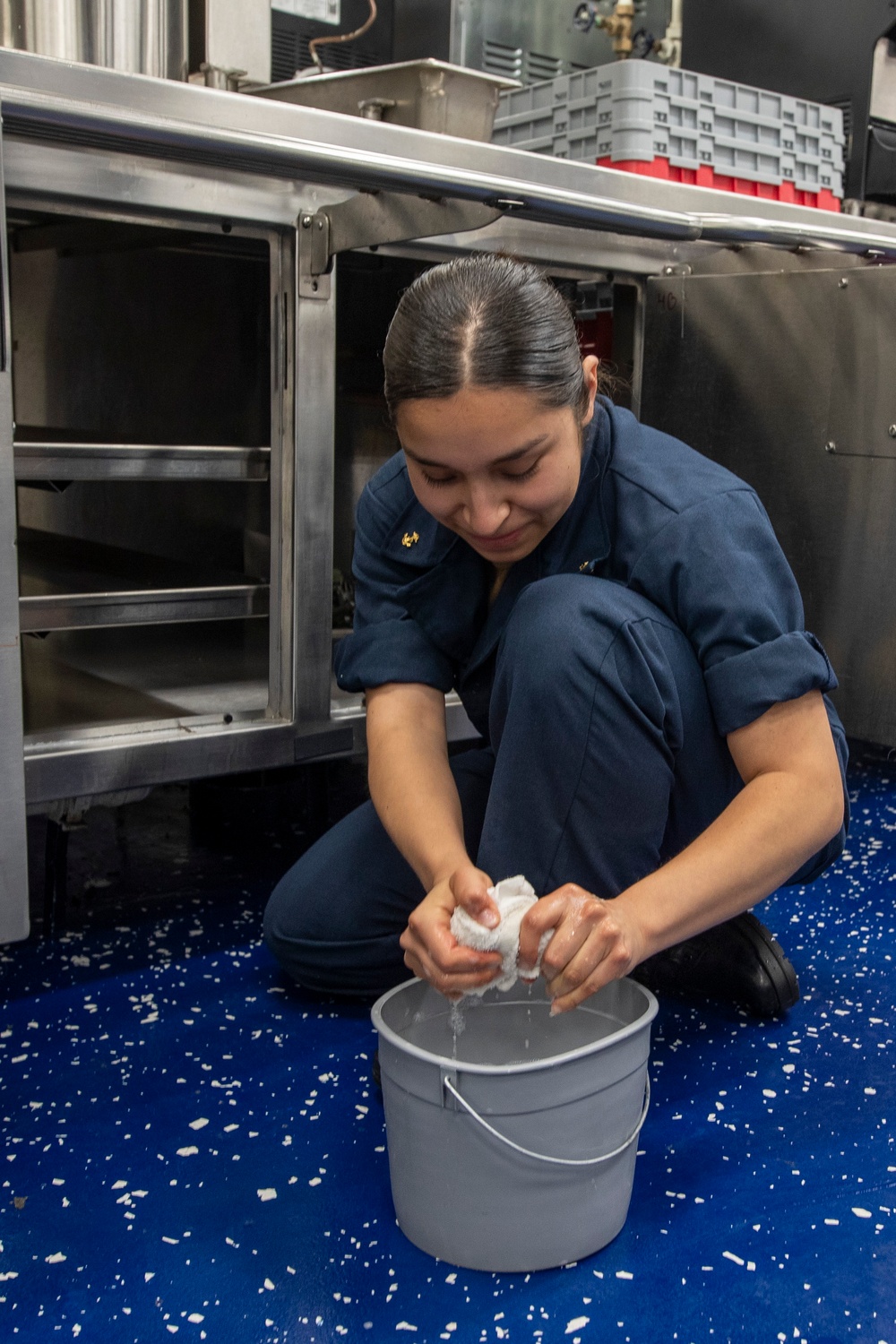 Midshipmen clean the mess decks aboard USS Tripoli