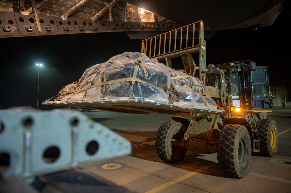 U.S. military personnel uses a forklift to load palletized equipment onto a U.S. Air Force C-17 Globemaster III aircraft