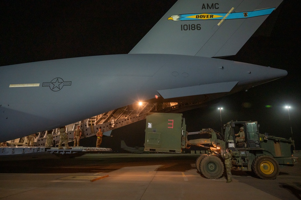 U.S. military personnel work side by side to oversee the loading of equipment onto a U.S. Air Force C-17 Globemaster III aircraft