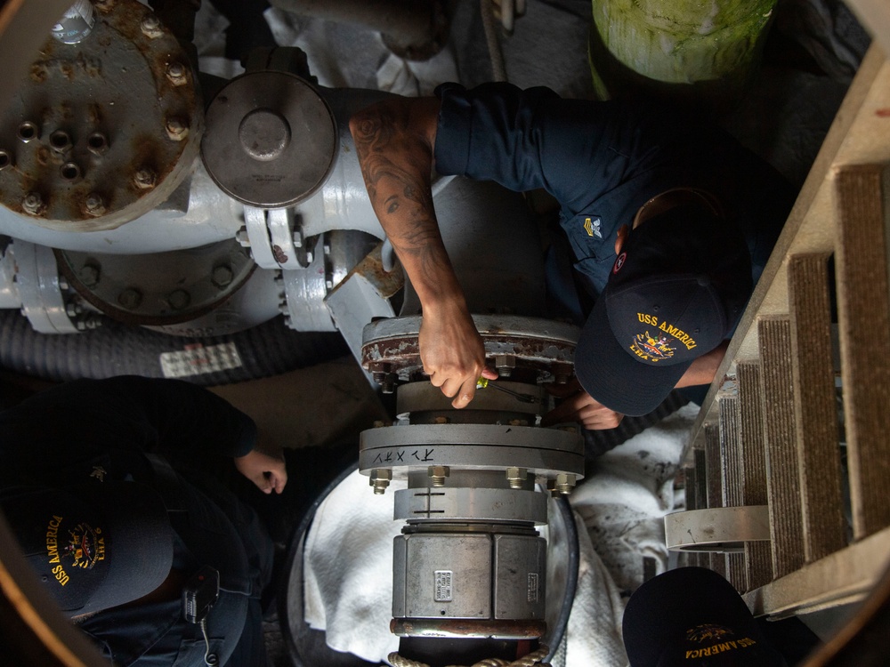 Sailors assigned to the USS America (LHA 6) handle a fueling hose