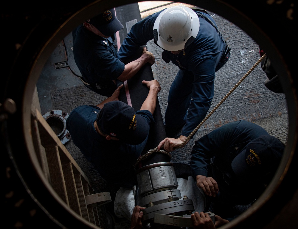 Sailors assigned to the USS America (LHA 6) handle a fueling hose