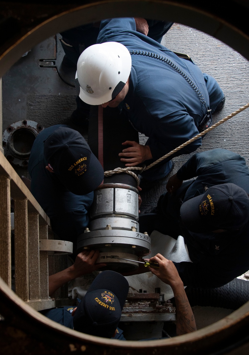 Sailors assigned to the USS America (LHA 6) handle a fueling hose