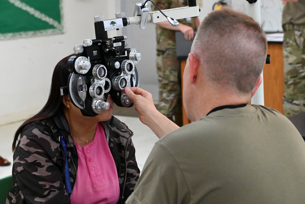 Optometrist operates phoropter for patient's glasses prescription